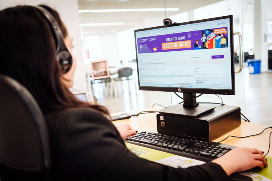 En la imagen aparece una estudiante con audífonos frente la monitor de la computadora entrando al servicio digital