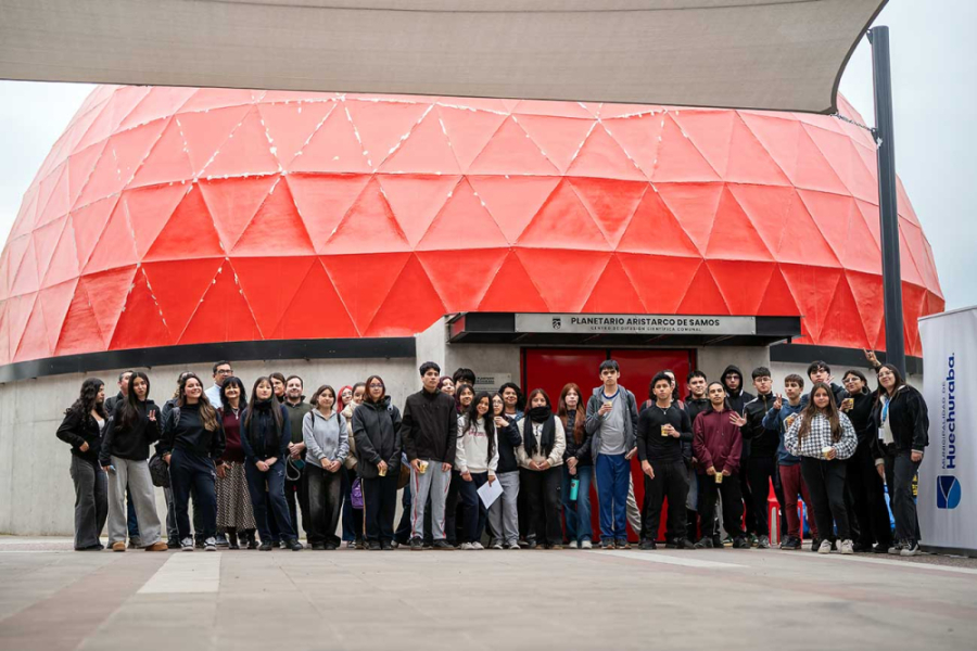 En la imagen se puede observar la cúpula y entrada del Planetario de Huechuraba. En su fachada aparecen estudiantes y académicos.