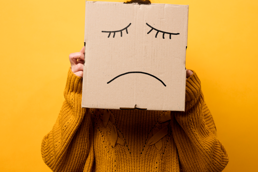 Cara triste dibujada en una caja de cartón.